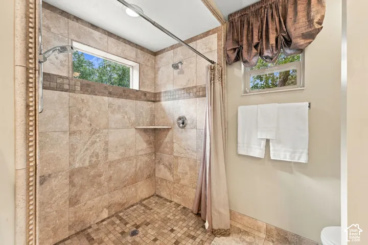 Primary Bathroom with Walk-in shower featuring large-format stone-look wall tiles, mosaic stone flooring, integrated tiled shelf, and chrome finish fixtures