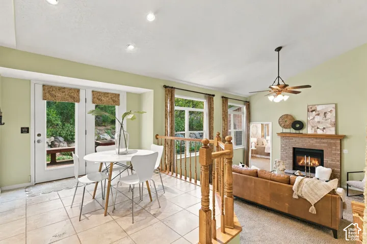 Vaulted ceilings, tile flooring, brick-surround fireplace, wooden balustrade, and recessed lighting