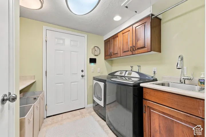 Laundry room featuring stained wood cabinetry, a utility sink with a high-arc faucet, solid surface countertops, and tile flooring
