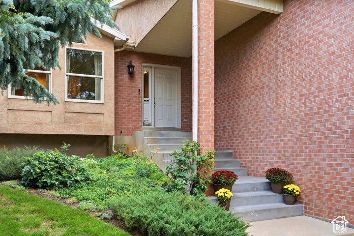 Exterior entry featuring red brick siding, a concrete staircase, and a paneled front door with a side light