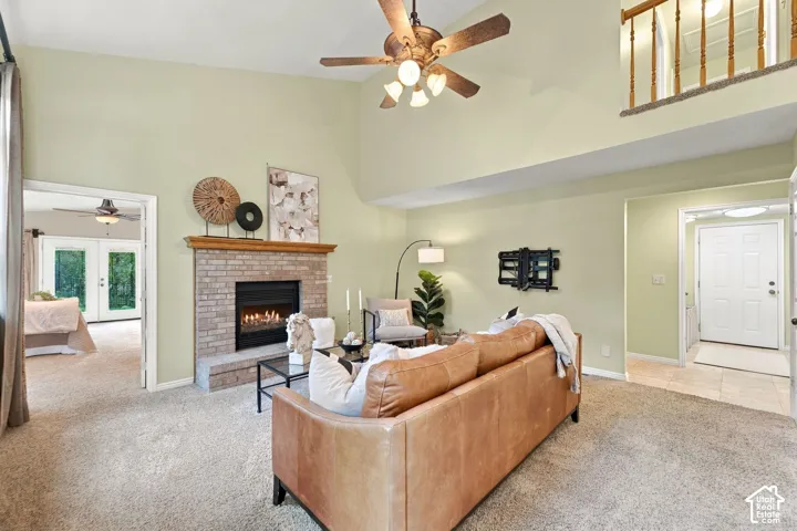 Vaulted ceiling, brick fireplace with a wood mantel, ceiling fan, and mezzanine overlook with wood railings
