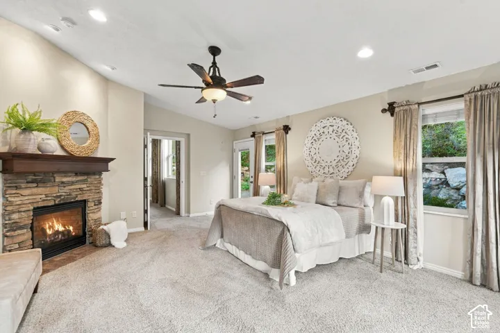 Fireplace with stone surround, wood mantel, carpeted flooring, vaulted ceiling, and recessed lighting
