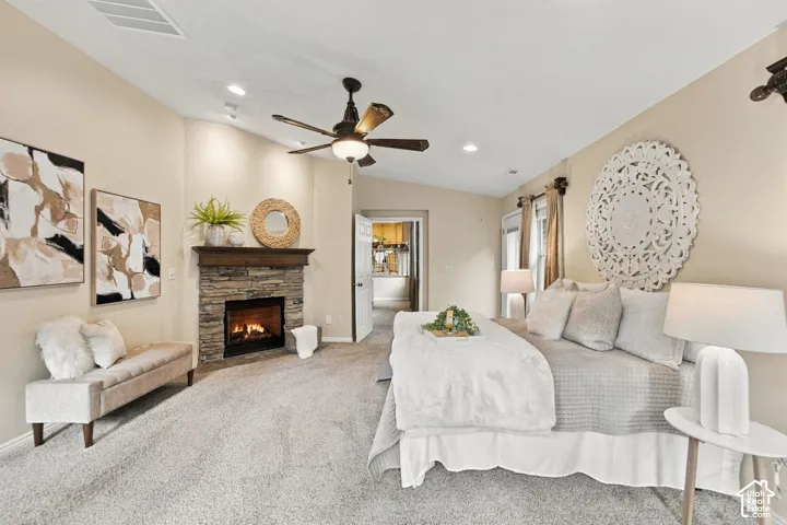 Primary bedroom with vaulted ceilings, neutral wall tones, carpeted flooring, a multi-blade ceiling fan with integrated light fixture, and double glass doors providing outdoor access
