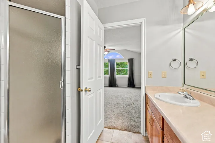 Second Floor Primary Ensuite Bathroom with Dual-sink vanity featuring a light-toned countertop, wood-finish cabinetry, a large wall-mounted mirror, and industrial-style multi-bulb lighting fixtures