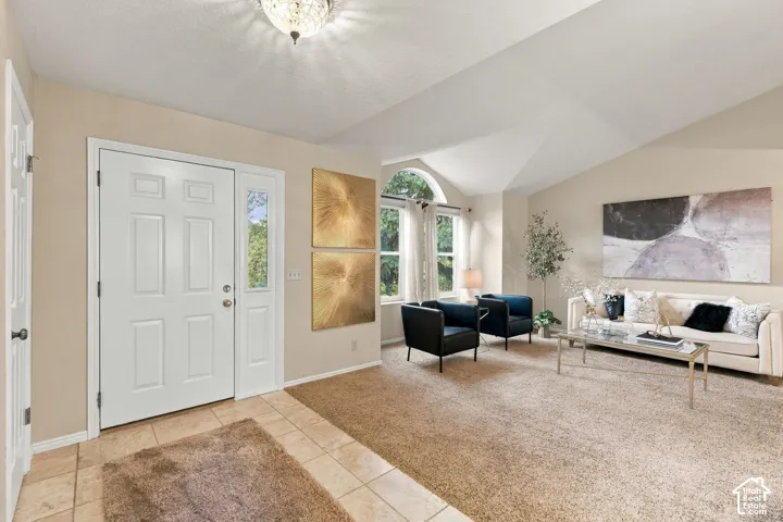 Entryway featuring tile flooring, vaulted ceilings, arched window, and flush-mount lighting