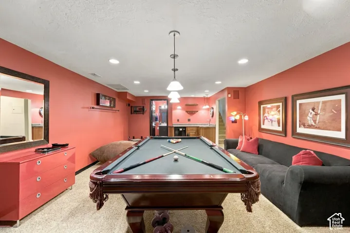Recessed lighting and a multi-pendant light fixture, a built-in wet bar with cabinetry, and a large wall-mounted mirror