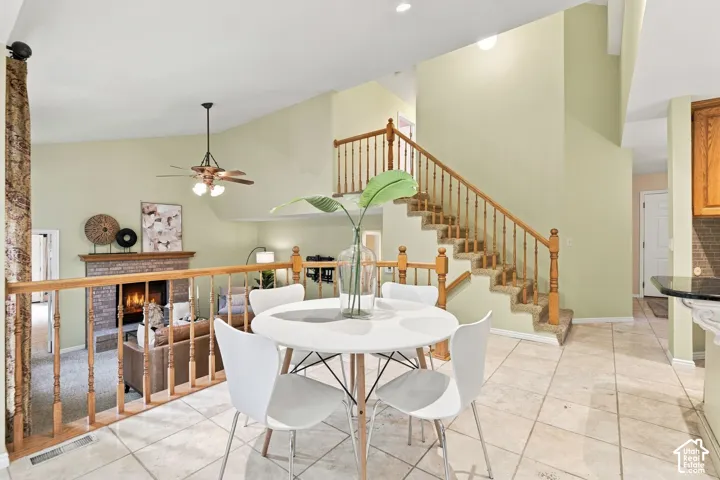 Vaulted ceilings, staircase with wooden balusters, stone-finish fireplace, and tile flooring