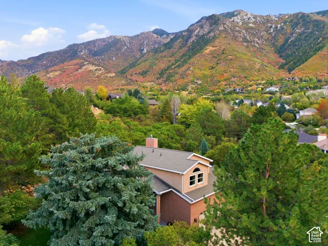 Two-story residence featuring a brick and stucco exterior, chimney stack, arched window, and mountain backdrop