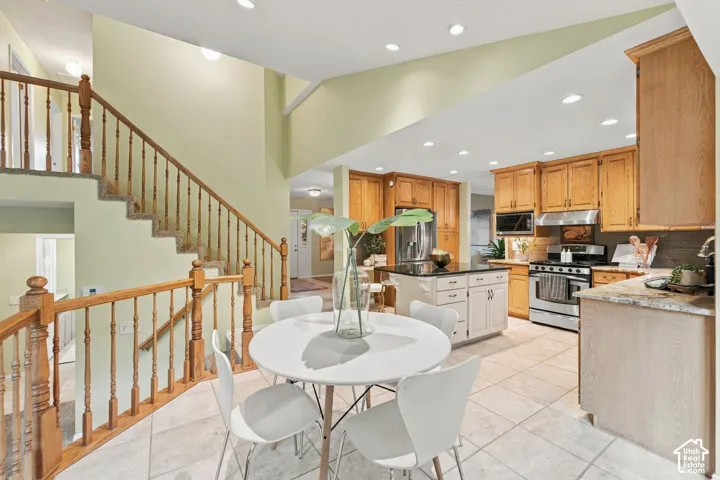 Kitchen featuring oak cabinetry, stone countertops, central island, tile flooring, and recessed lighting