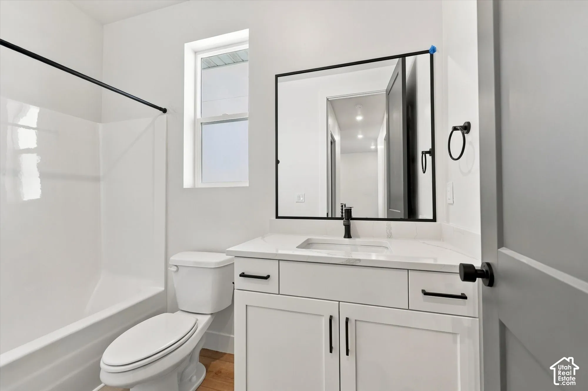 Bathroom featuring a white shaker-style vanity with stone-composite countertop, matte black hardware, integrated rectangular basin, and a square framed mirror