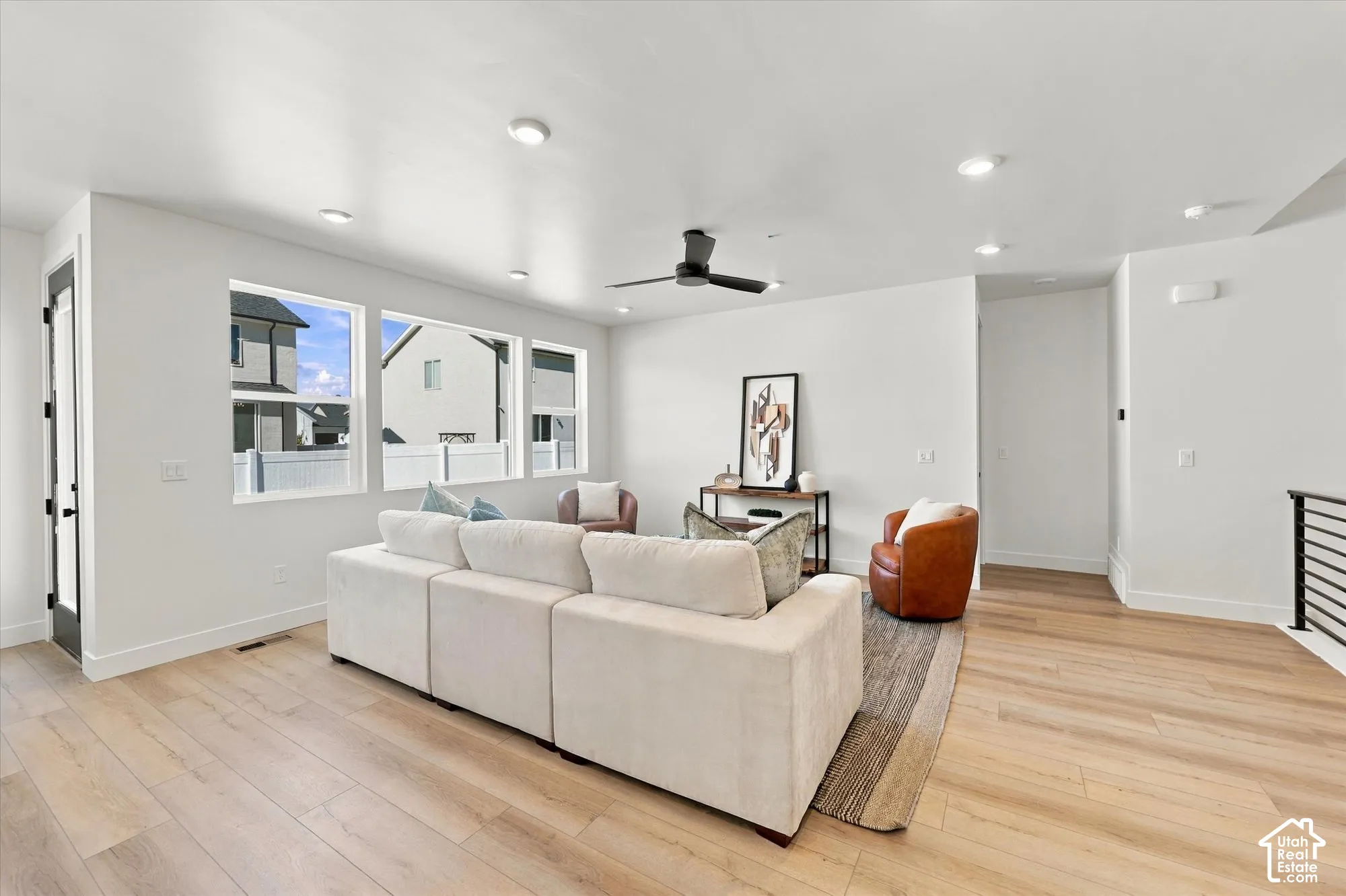 Open interior space featuring wood-finish flooring, recessed lighting, expansive windows, and a matte black ceiling fan