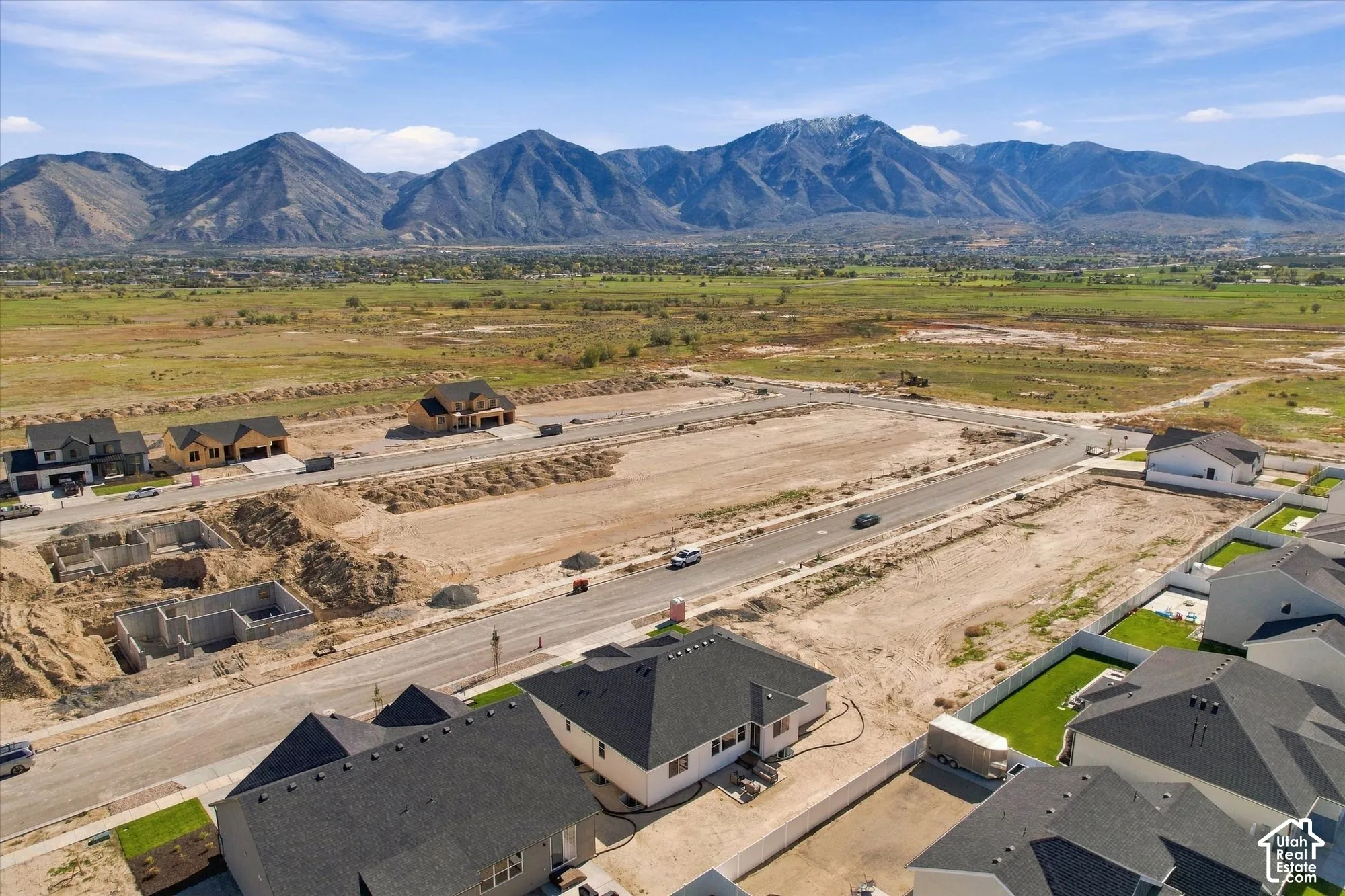 Aerial perspective showcasing a residential subdivision featuring paved streets and a backdrop of mountain ranges