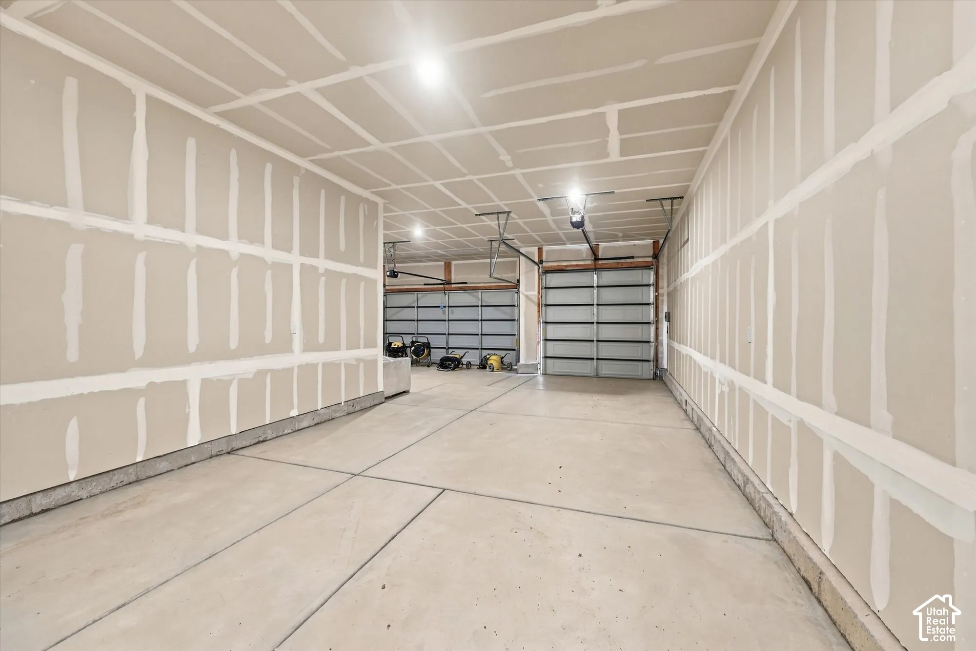 Multi-vehicle garage featuring unfinished drywall, concrete flooring, and multiple overhead metal garage doors