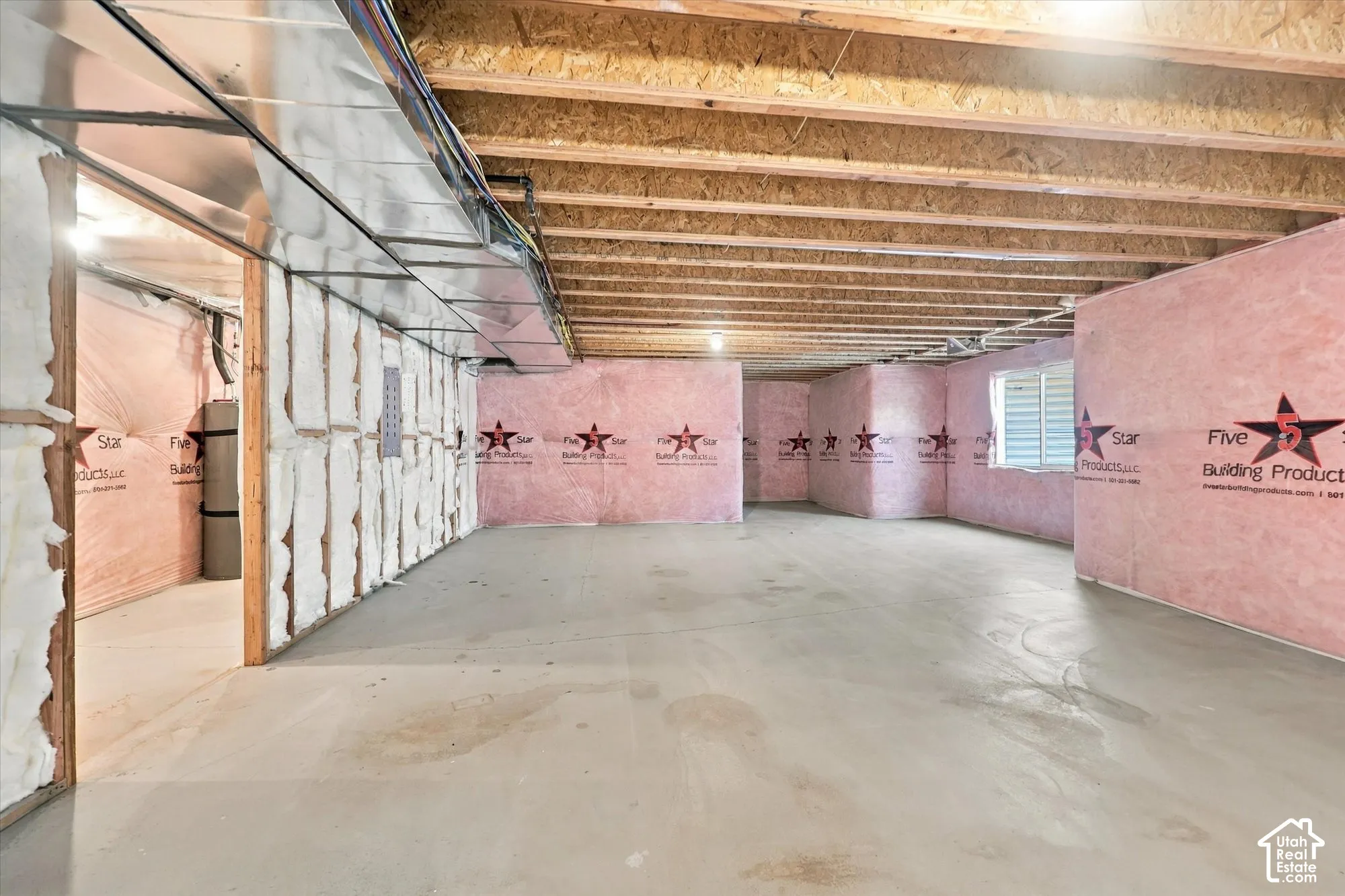 Unfinished lower level featuring concrete flooring, exposed wooden ceiling joists, insulated perimeter walls, and a recessed window