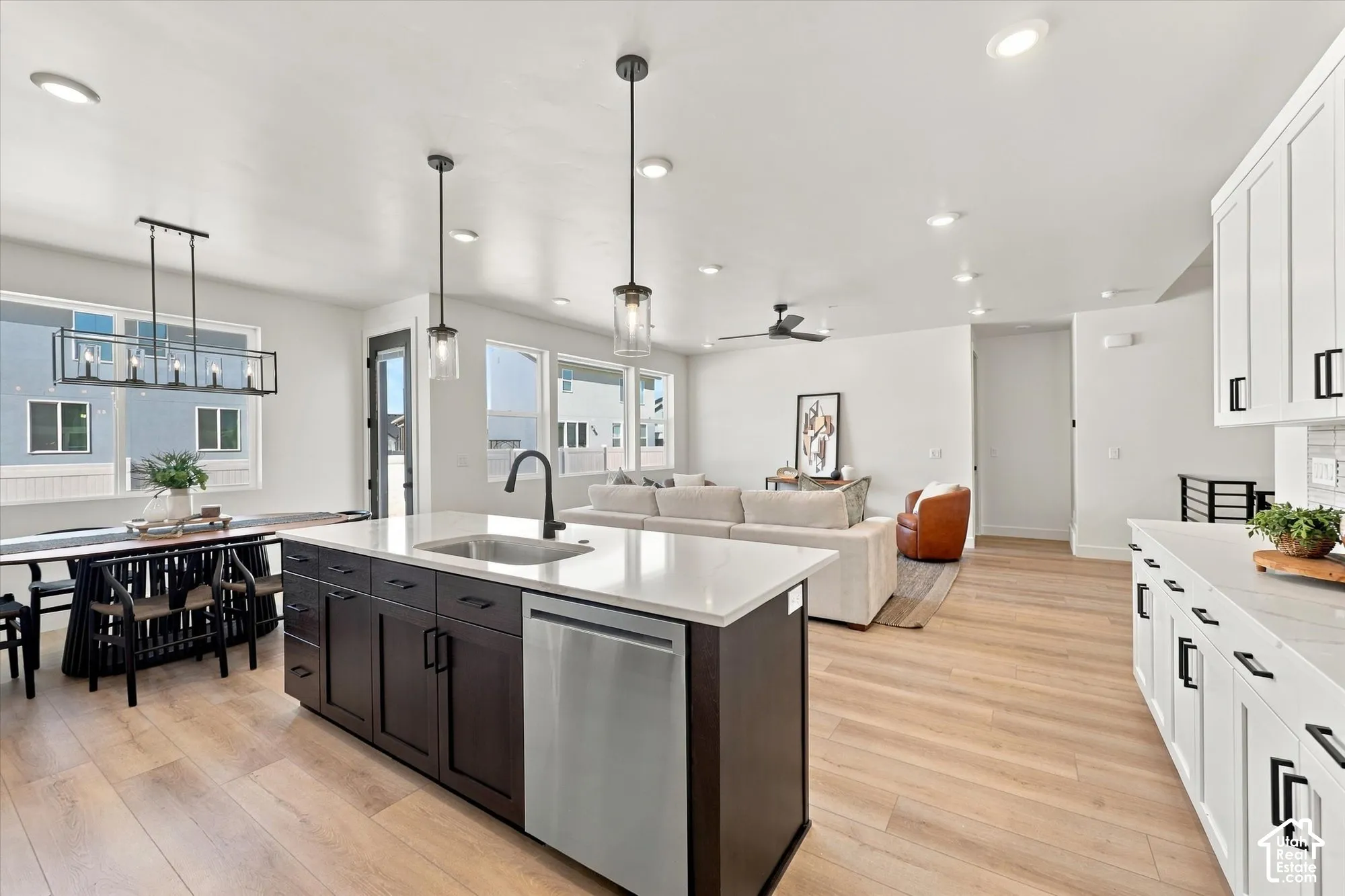 Kitchen featuring a central island with a quartz countertop, stainless steel dishwasher, wood-finish flooring, recessed lighting, and pendant fixtures