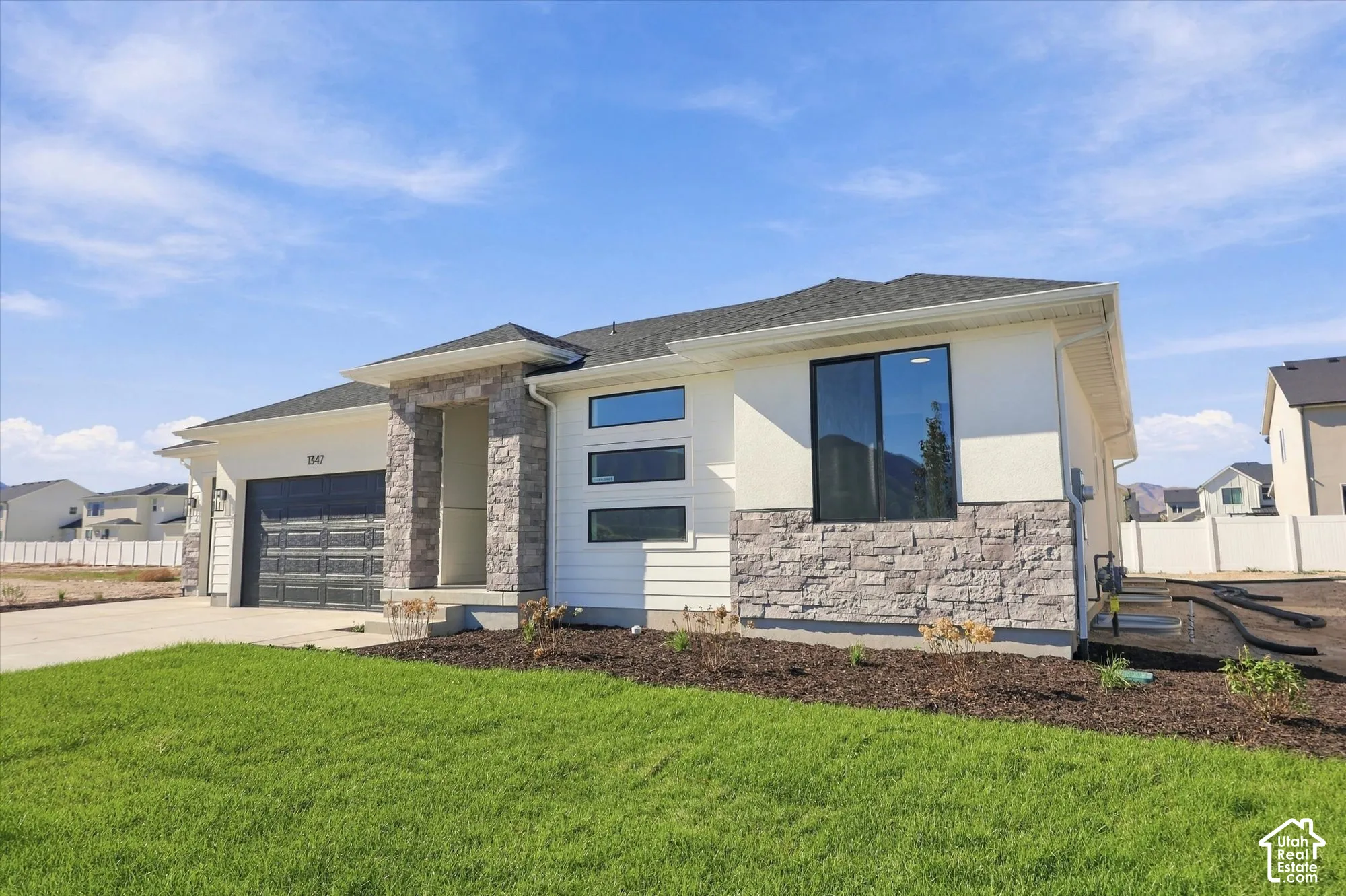 Single-story exterior featuring a mix of stucco and stone veneer siding, horizontal lap siding accents, a multi-paneled garage door, and a horizontal stacked window configuration