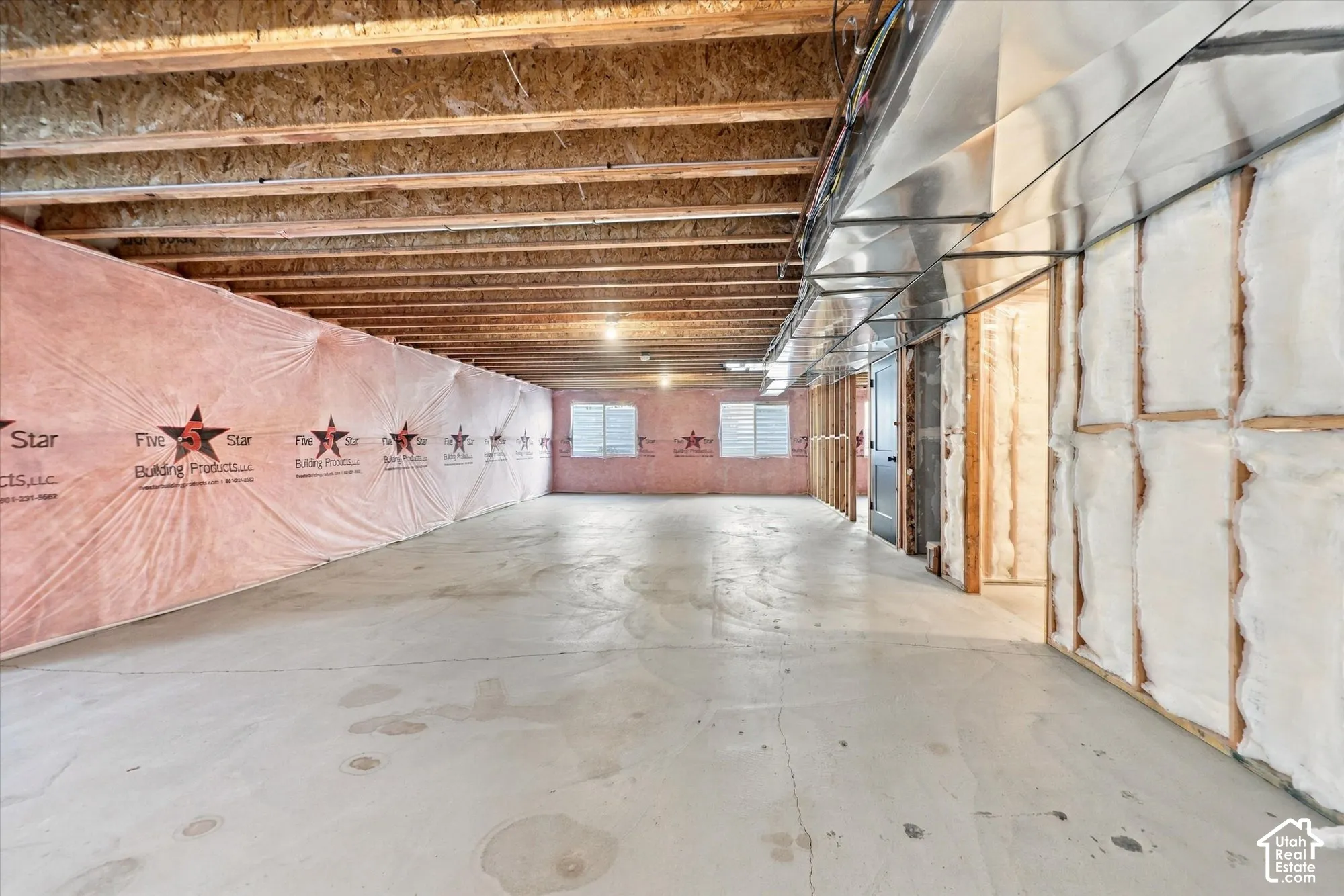 Unfinished basement featuring concrete flooring, exposed wooden ceiling joists, metal HVAC ductwork, and wall insulation