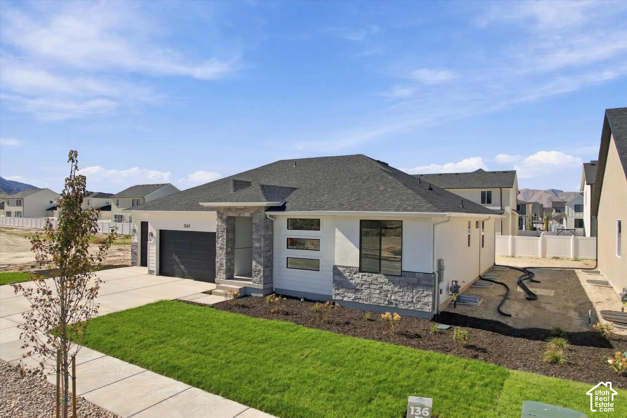 Single-story residence featuring a combination of horizontal siding and stone veneer, asphalt shingle roof, attached garage, and landscaped front yard