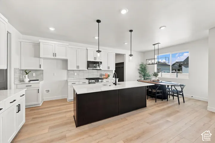 Kitchen featuring white cabinetry, wood-finish flooring, a central island with a contrasting dark base, quartz countertops, and recessed lighting
