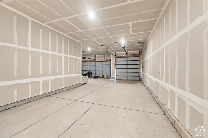 Multi-vehicle garage featuring unfinished drywall, concrete flooring, and multiple overhead metal garage doors