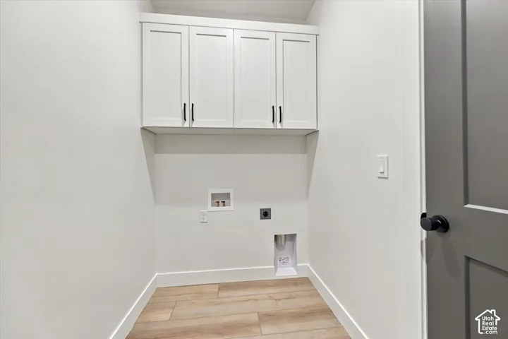 Utility area featuring white shaker-style wall cabinetry with dark hardware, wood-finish flooring, and a neutral color palette