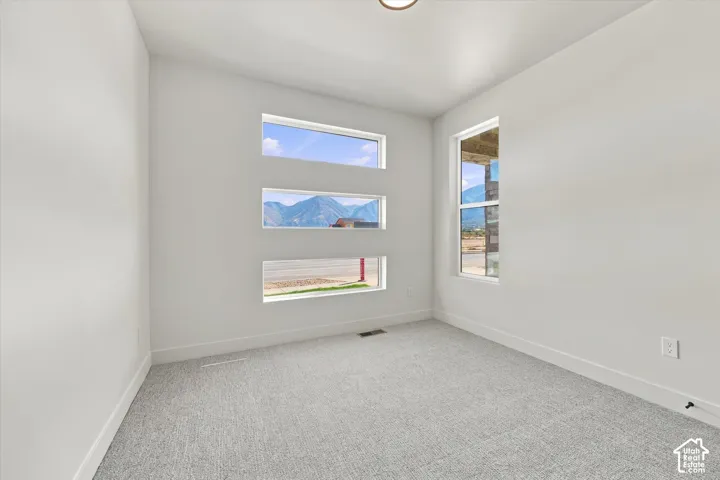 Neutral-toned interior space featuring three stacked horizontal windows, a full-height vertical window, and wall-to-wall carpeting