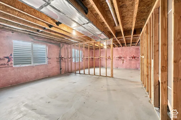 Unfinished interior space featuring exposed wood-stud framing, concrete flooring, exposed ceiling joists, and multiple egress windows