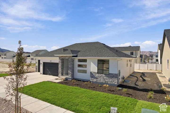 Single-story residence featuring a combination of horizontal siding and stone veneer, asphalt shingle roof, attached garage, and landscaped front yard