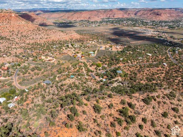 Aerial perspective of expansive high-desert terrain featuring native vegetation, prominent red rock formations, and arid topography