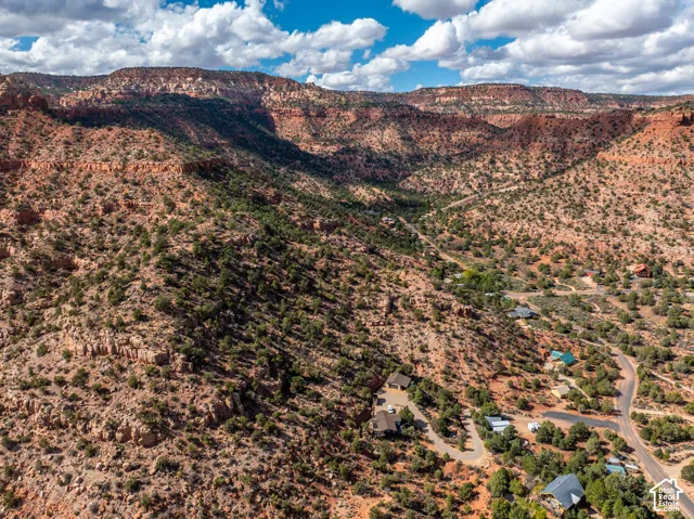 Aerial perspective of desert terrain featuring rugged topography, native shrubbery, scattered pi