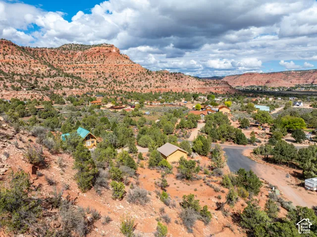 Aerial perspective featuring desert terrain, native vegetation, rock formations, and paved road access