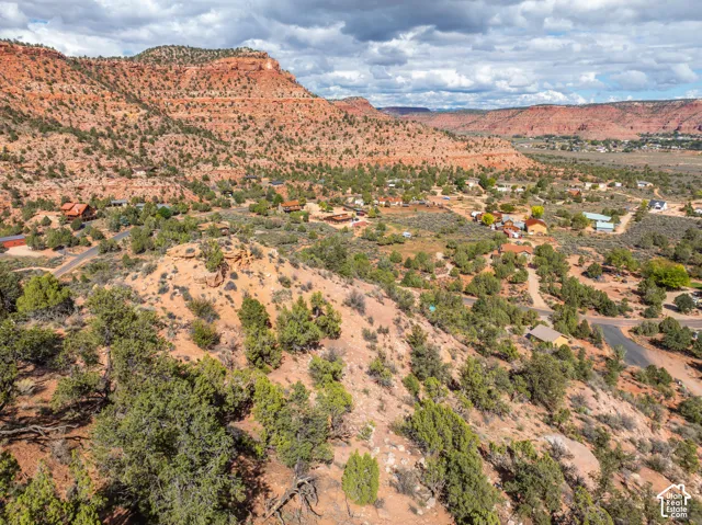 Elevated desert terrain featuring natural sandstone formations, native scrub brush, and expansive red rock scenery