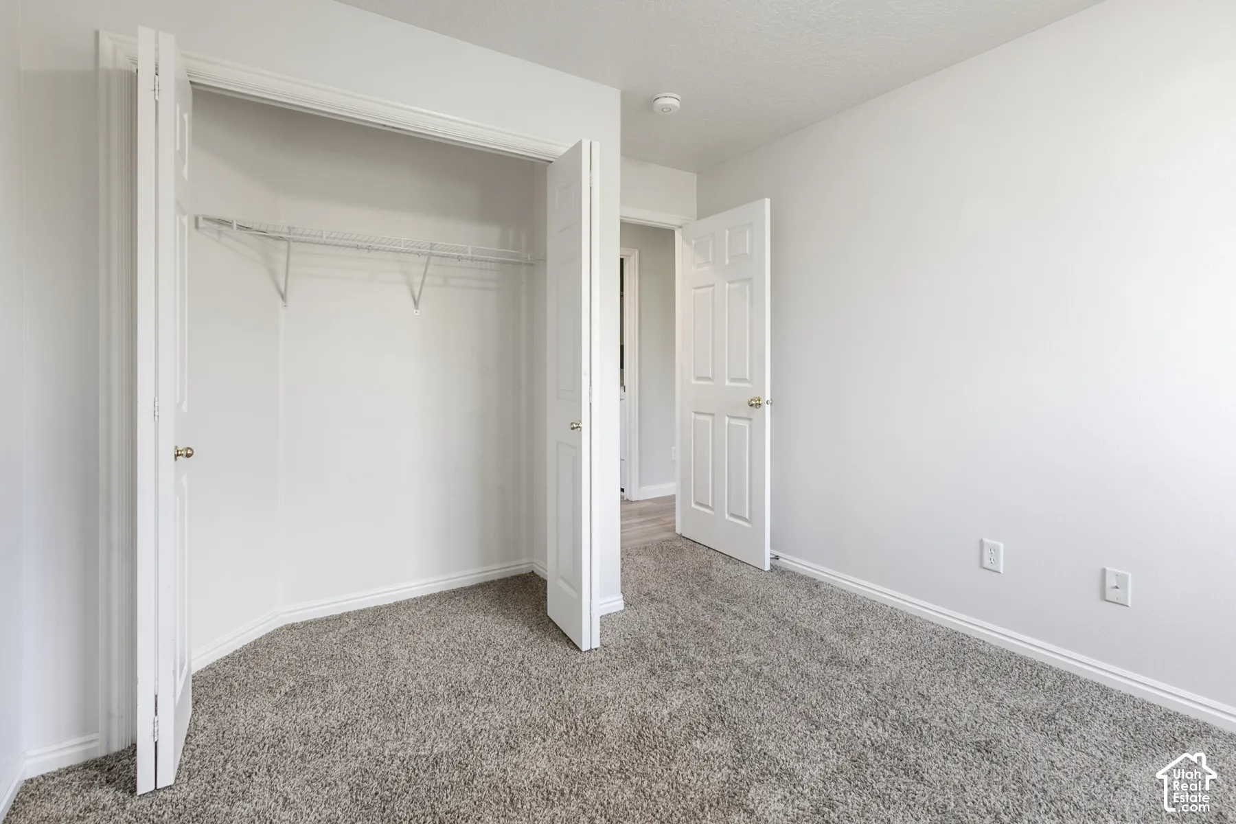 Room featuring neutral wall-to-wall carpeting, a reach-in closet with wire shelving, and multi-panel interior doors