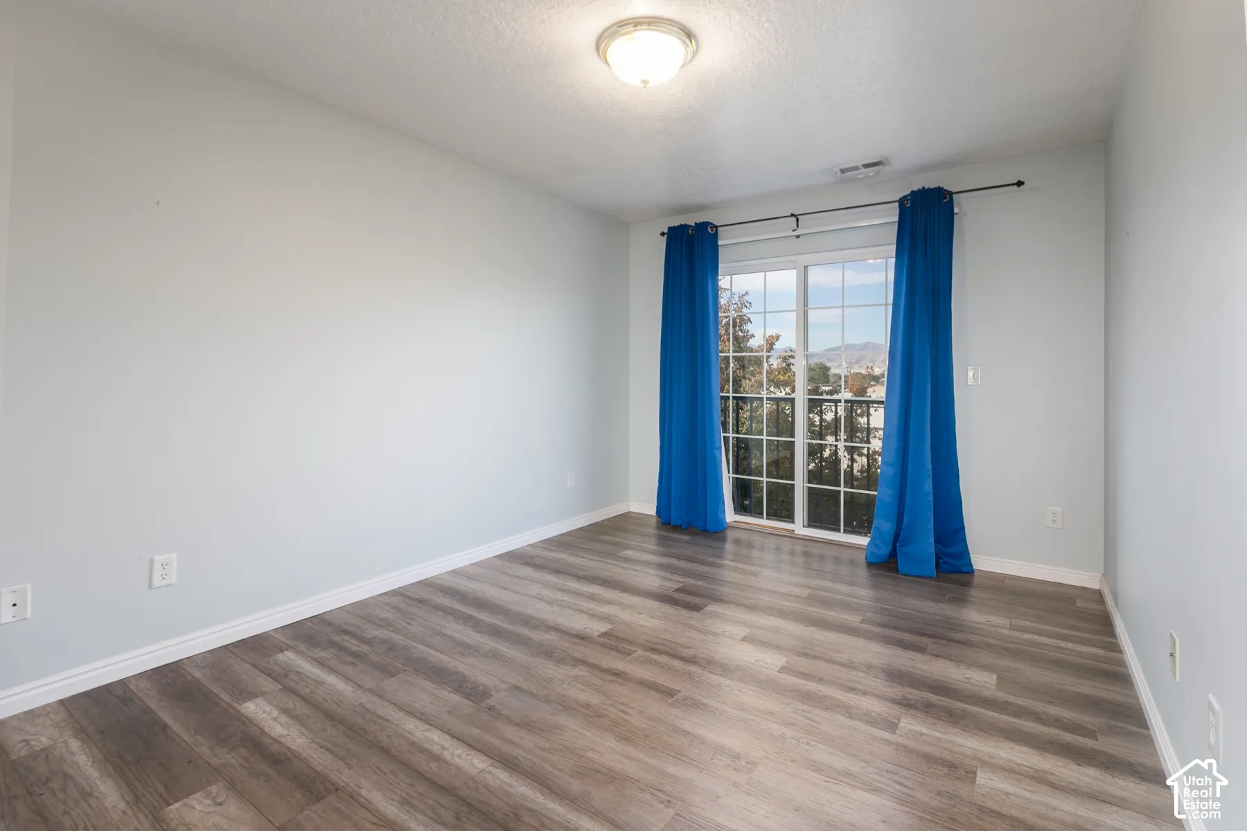 Interior room featuring wood-finish flooring, sliding glass doors, and a flush-mount ceiling light fixture