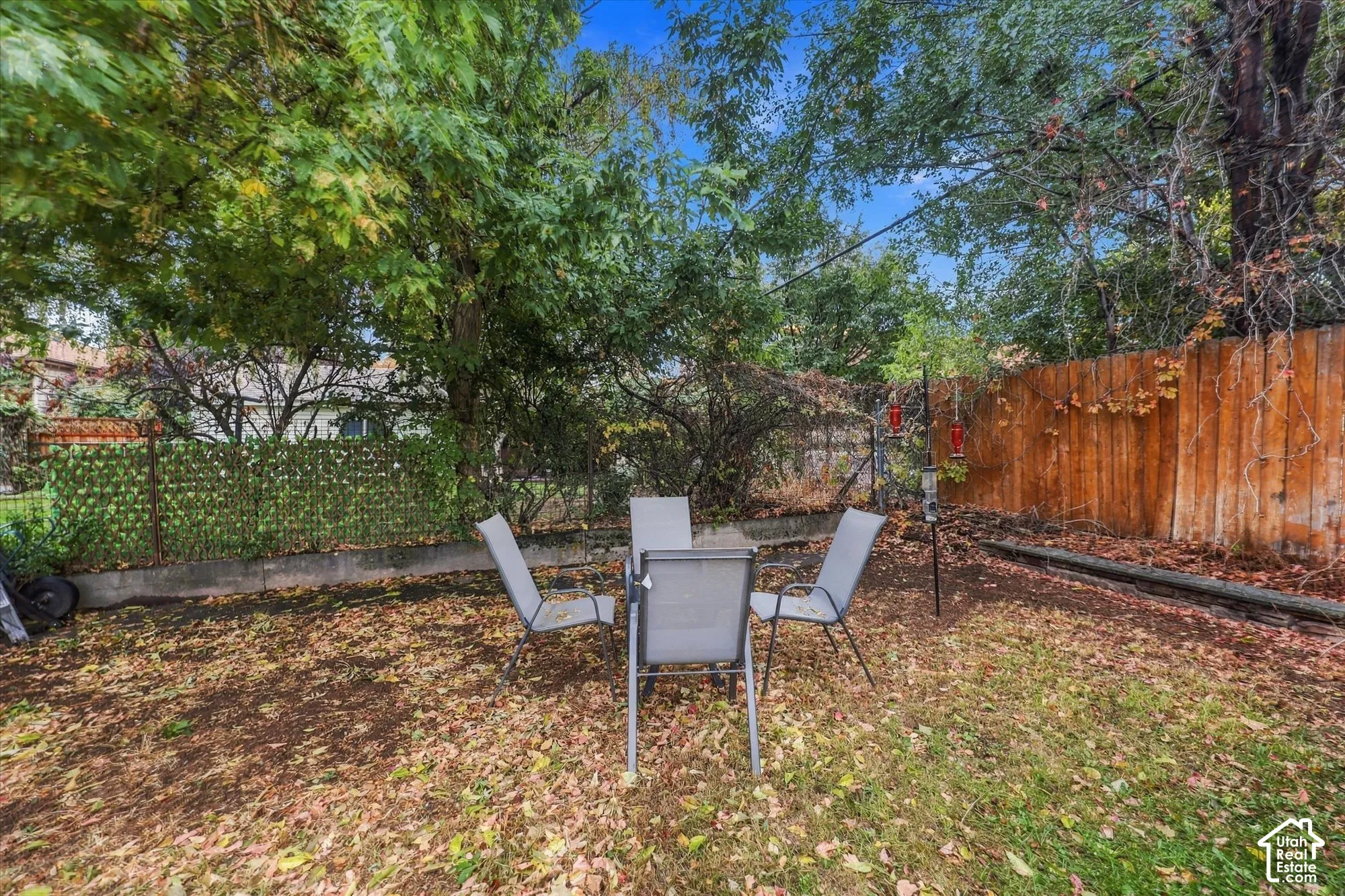 Backyard area featuring mature trees, wood privacy fencing, concrete retaining wall, and latticed metal screening