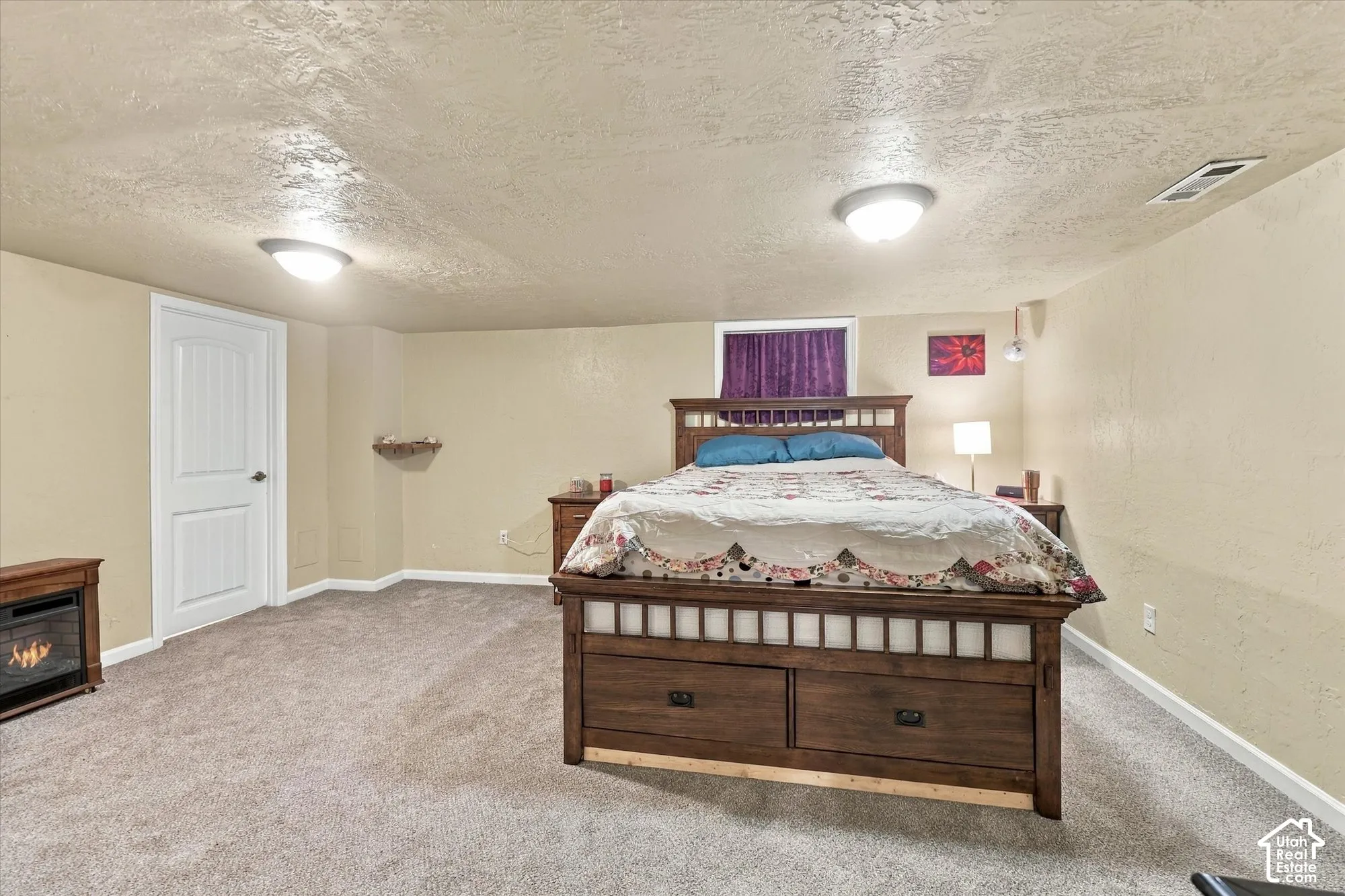Room featuring neutral wall-to-wall carpeting, textured ceiling, two flush-mount light fixtures, and a six-panel interior door