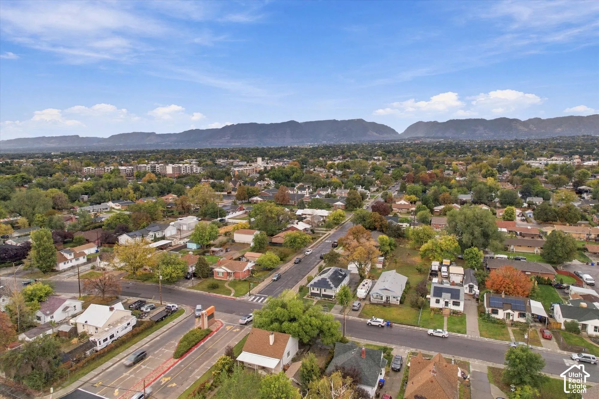 Aerial perspective featuring a residential setting with mature trees and a prominent mountain range backdrop