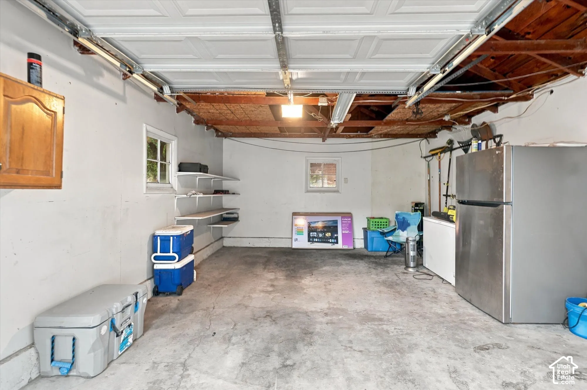 Enclosed garage featuring concrete flooring, built-in shelving, two windows, and an overhead sectional garage door