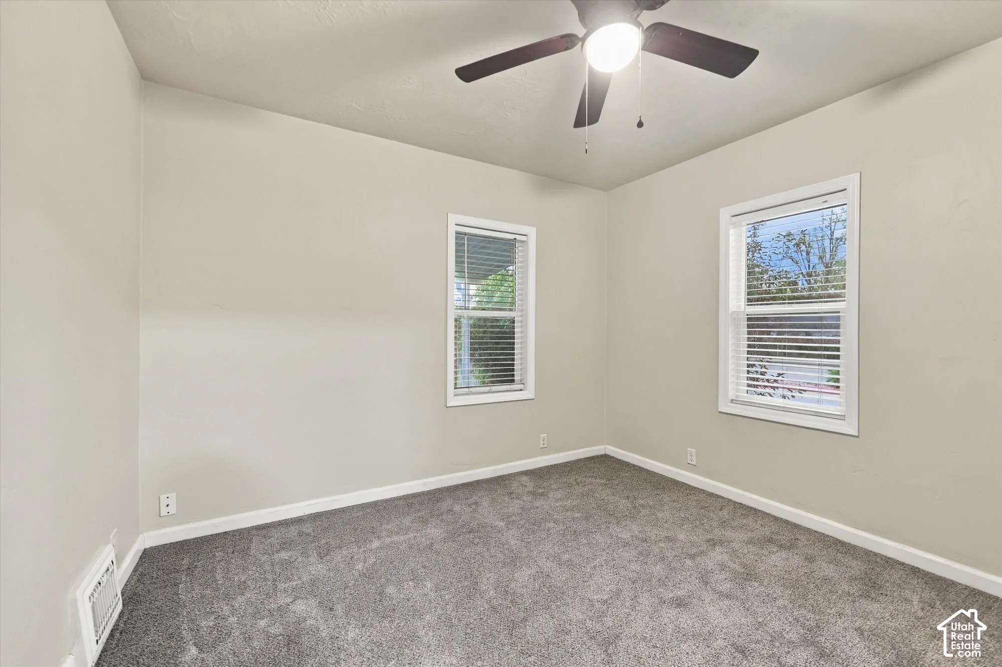 Neutral-toned wall finish, wall-to-wall carpeting, dual windows with integrated blinds, and a ceiling fan with integrated light fixture