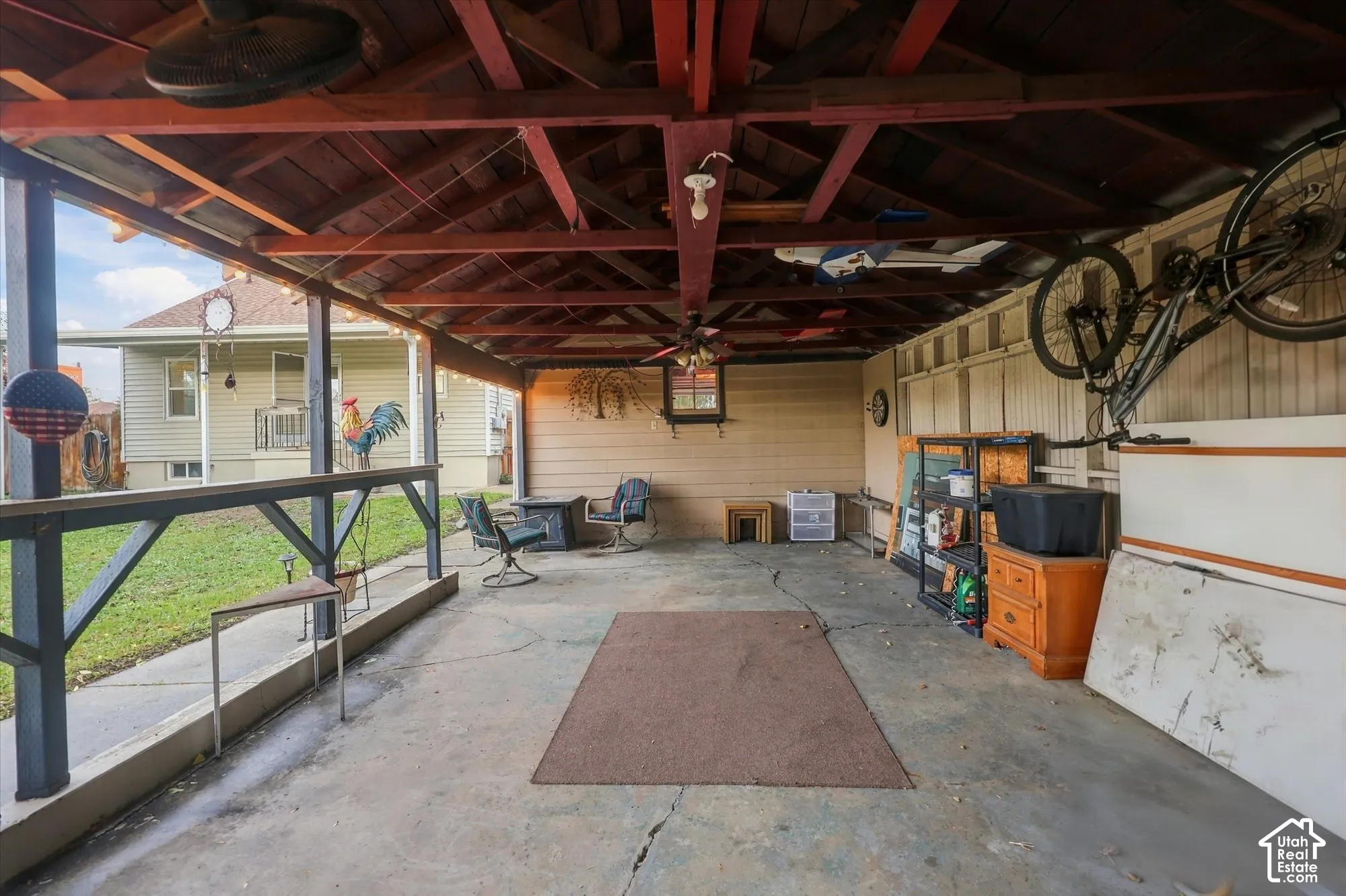 Covered outdoor patio with an exposed timber ceiling, concrete flooring, and perimeter railing