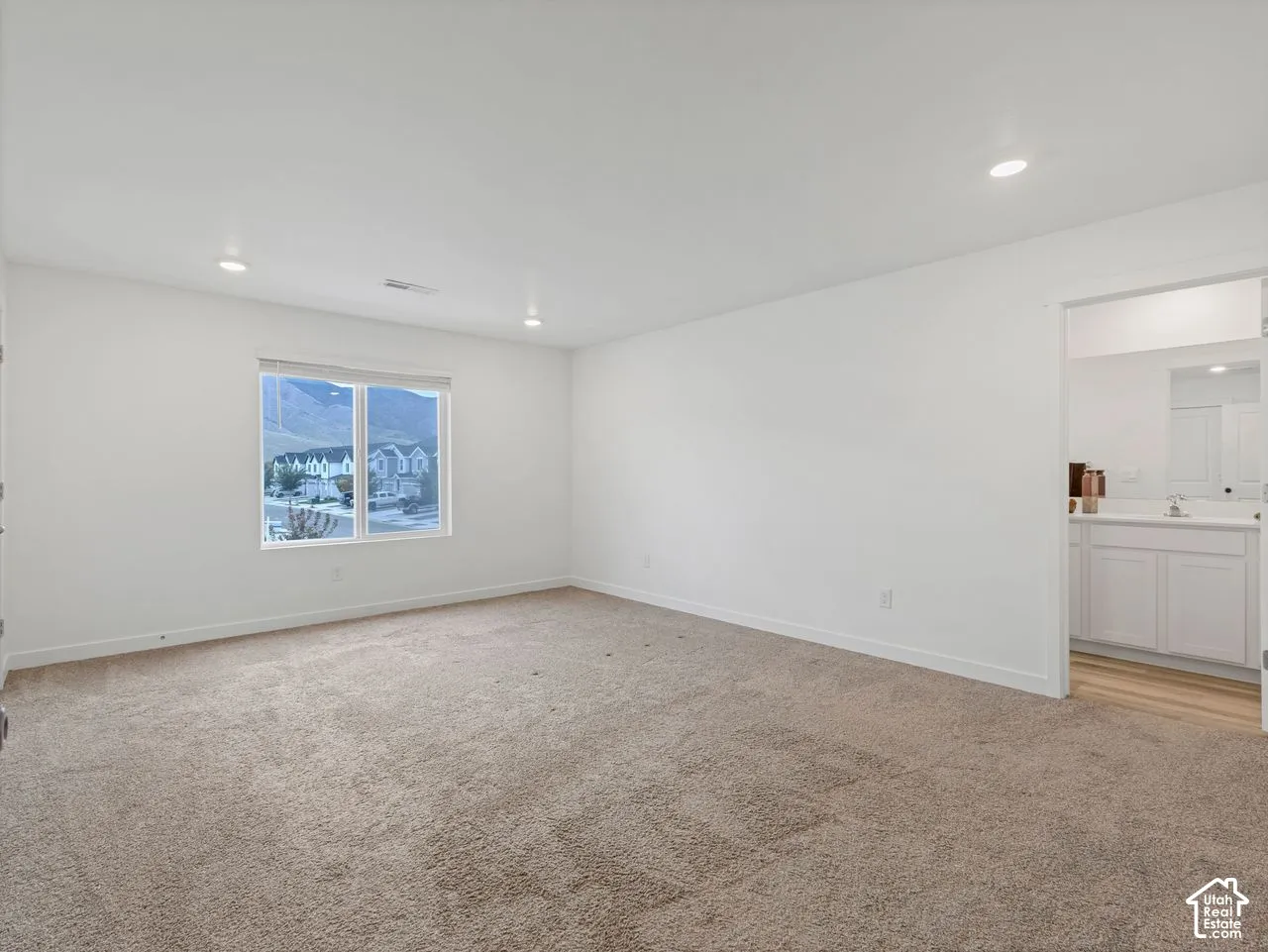 Spacious interior featuring neutral-toned carpeting, recessed lighting, and a window with mountain scenery
