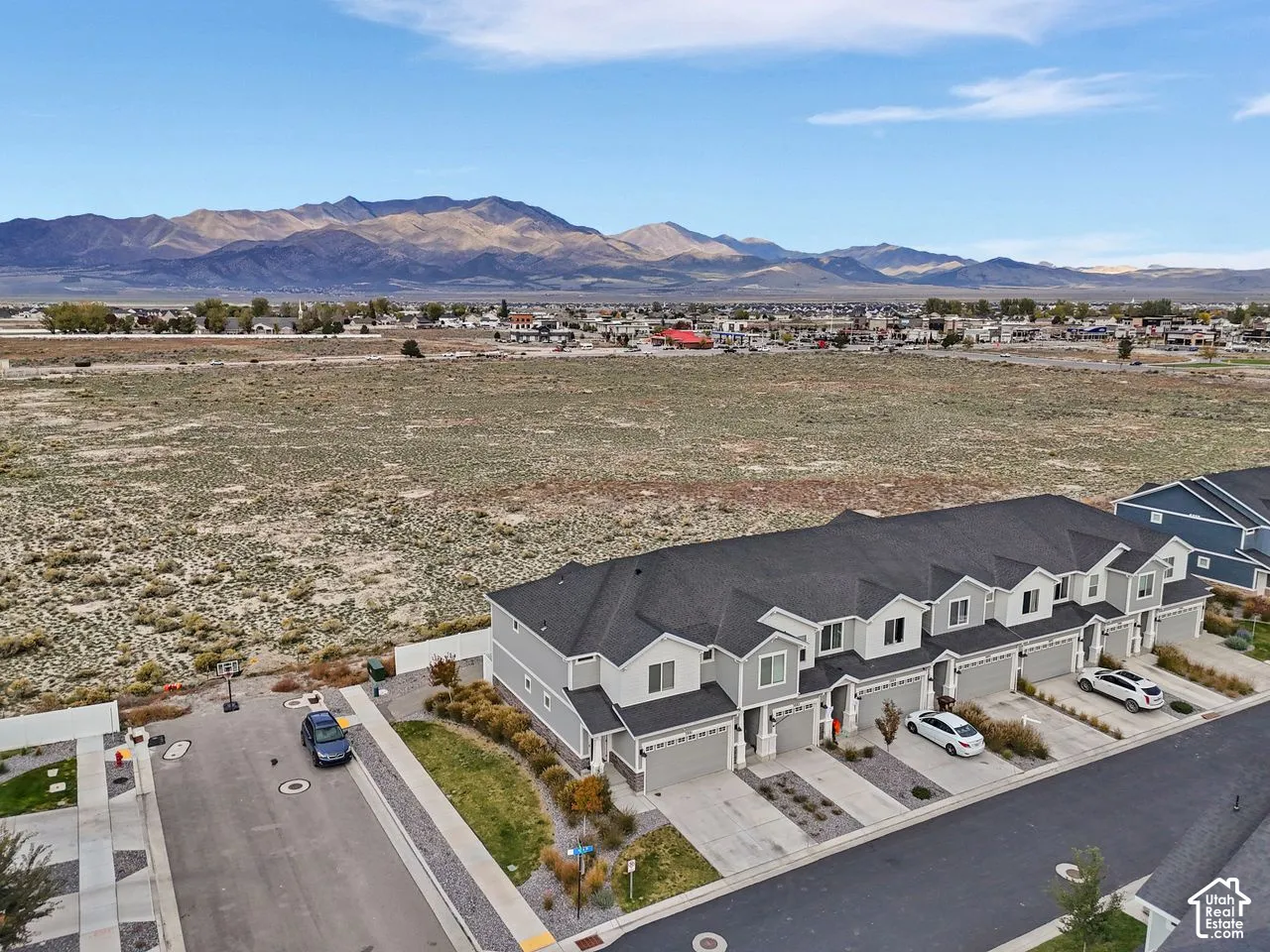 Aerial perspective of a multi-unit residential structure featuring a gable roofline, attached multi-car garages, and a mountainous backdrop