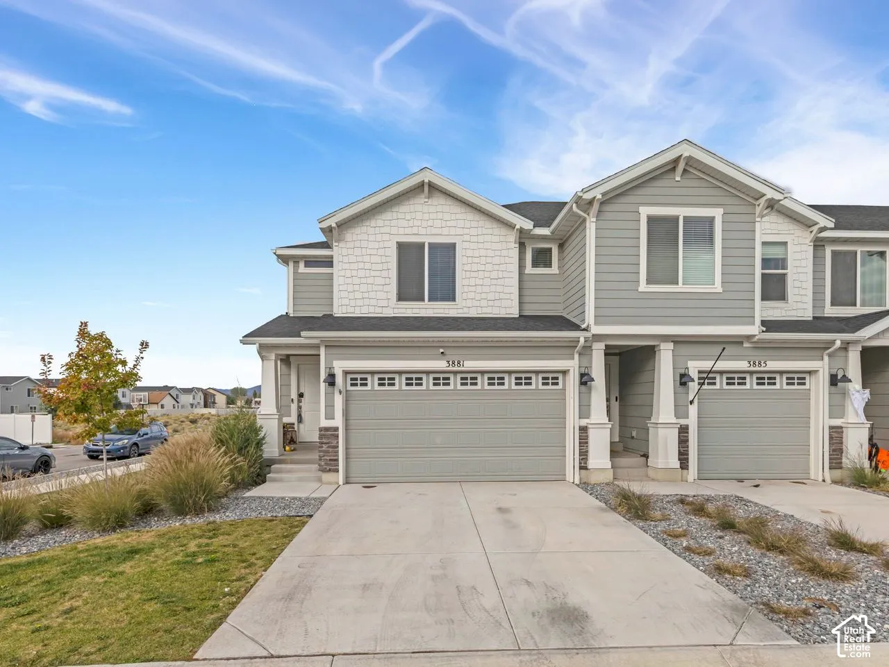 Multi-level exterior featuring horizontal lap siding, decorative shingle accents, stone veneer detailing, an attached two-car garage, and pillared covered entryway