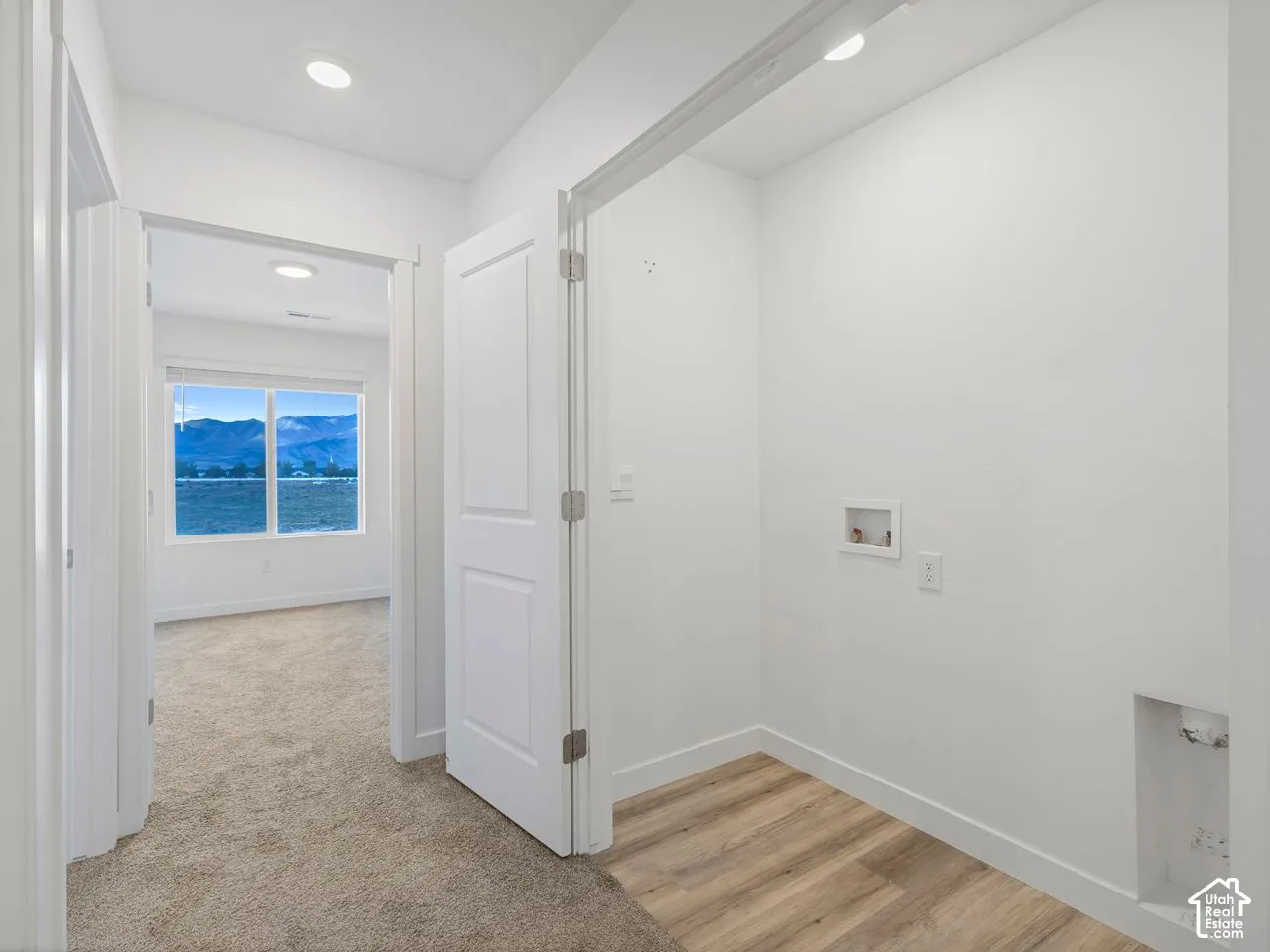 Laundry area with wood-finish flooring, recessed lighting, and wall-mounted utility connections, featuring interior millwork and carpeting in the surrounding space