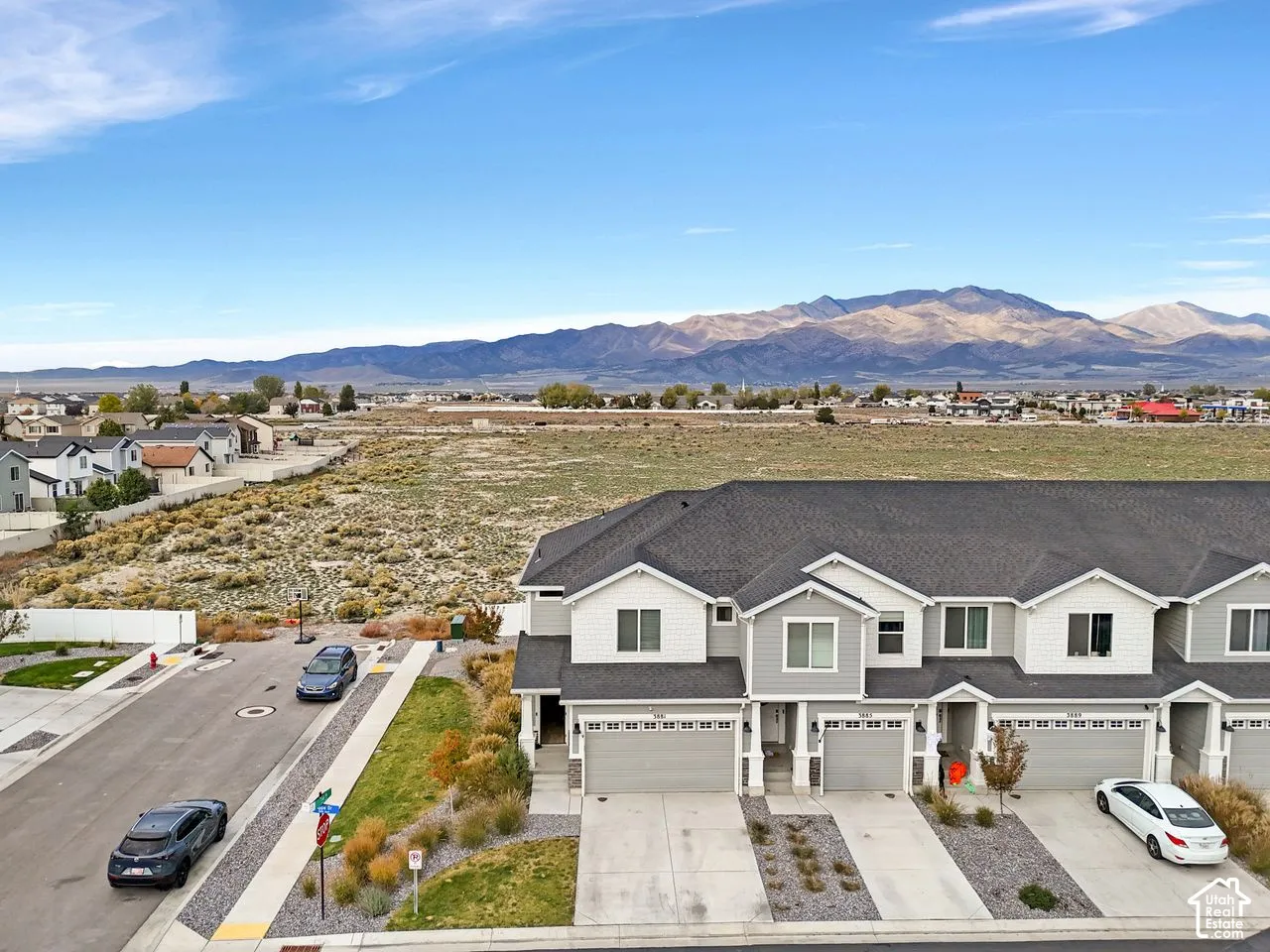 Multi-unit property with a shingle roof, lap siding, multi-car garages, concrete driveways, and mountain backdrop