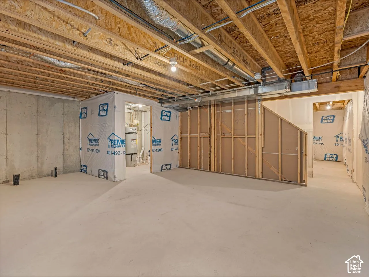 Unfinished basement featuring exposed wood-joist ceiling, concrete foundation walls, concrete floor, and framed partition walls