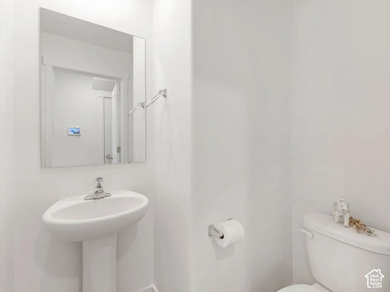 Pedestal sink featuring a polished chrome faucet, wall-mounted mirror, and chrome towel ring