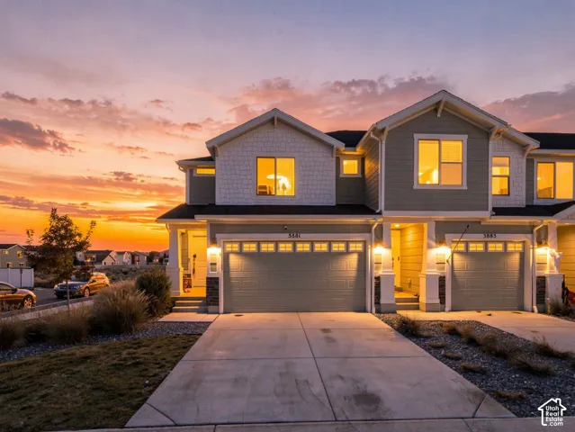 Multi-unit exterior featuring dual-gabled rooflines, lap and shake siding, stone masonry accents, and concrete driveways with attached multi-car garages
