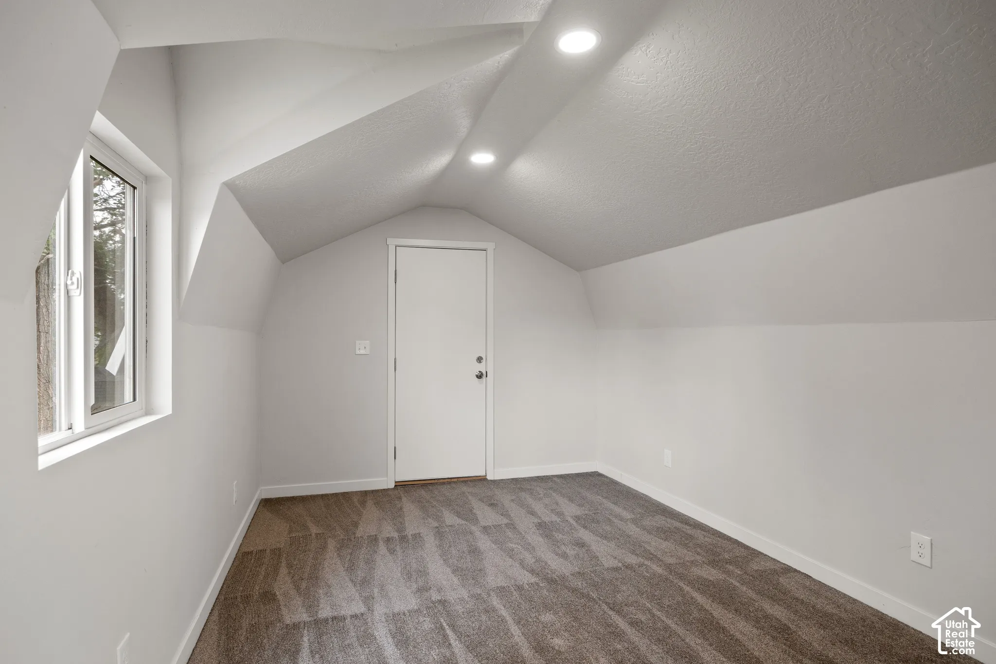 Vaulted ceilings, neutral carpeting, recessed lighting, and a single-pane window
