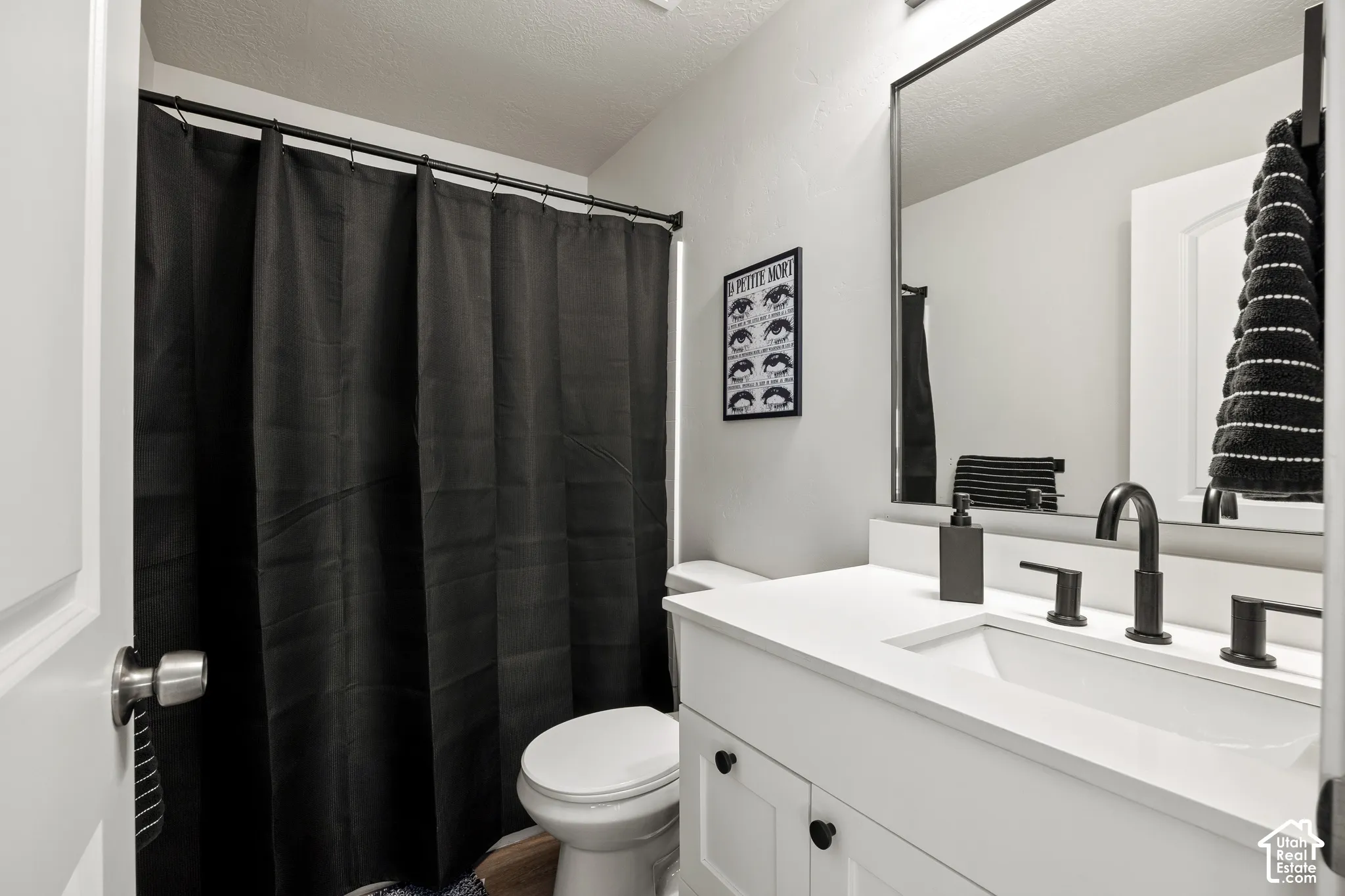 Bathroom featuring a white vanity cabinet, solid-surface countertop with an integrated rectangular sink, matte black widespread faucet, and a large rectangular mirror with a black frame